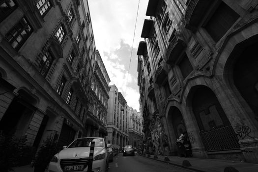 Black and white view of a street in Istanbul with historic buildings and cars, offering a dramatic urban perspective.