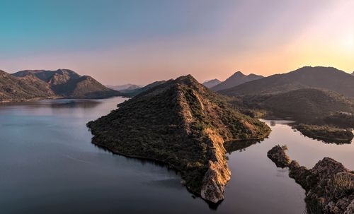 Free Breathtaking aerial view of a tranquil lake surrounded by majestic mountains at sunset, perfect for nature and travel themes. Stock Photo