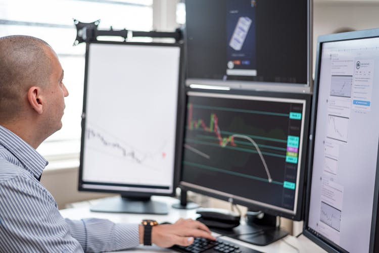 Trader Looking At Charts In The Monitors