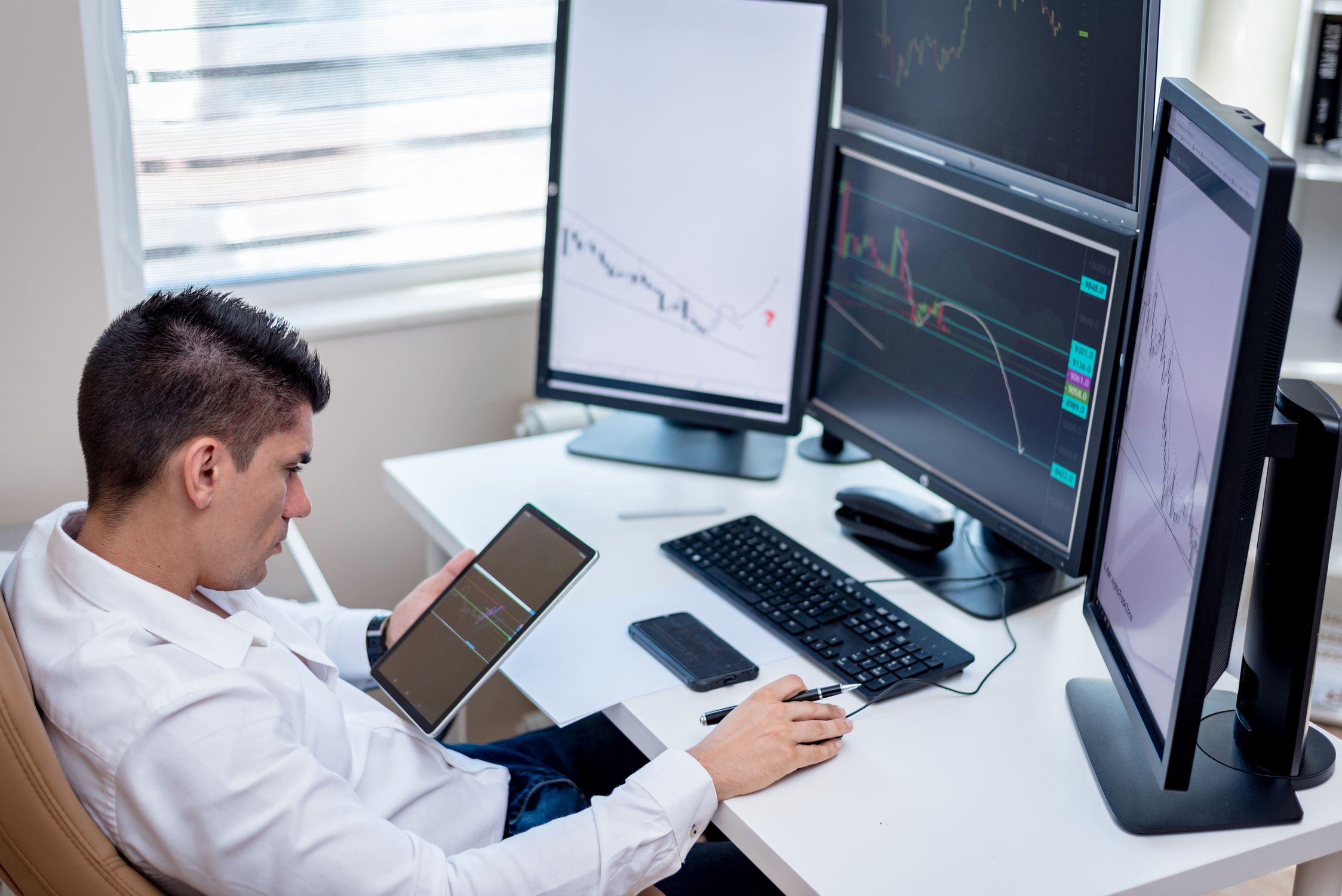 Professional trader at multi-monitor workstation analysing FX options and market data