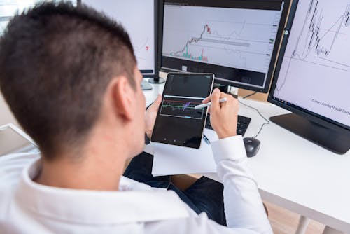 A Man Looking at the Graphs on Black Tablet