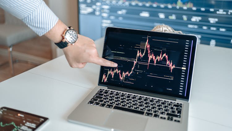 A Man Pointing At Chart On A Laptop Screen