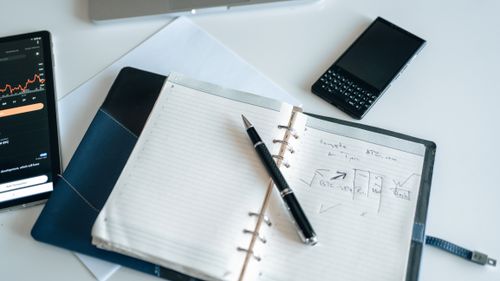Free Flat lay of a workspace with a notebook, pen, and electronic devices, ideal for productivity. Stock Photo