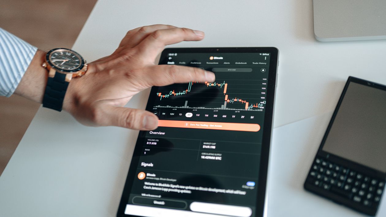 Free A person analyzing cryptocurrency market trends on a tablet device displaying digital charts. Stock Photo
