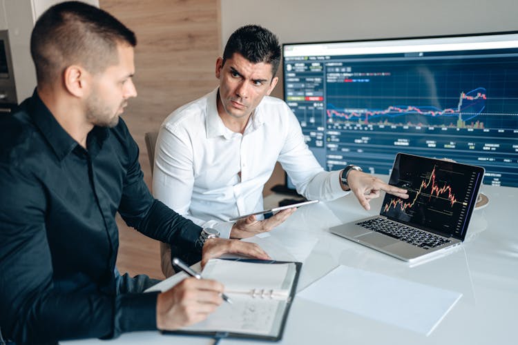 Man In White Long Sleeves Pointing Diagram On Laptop