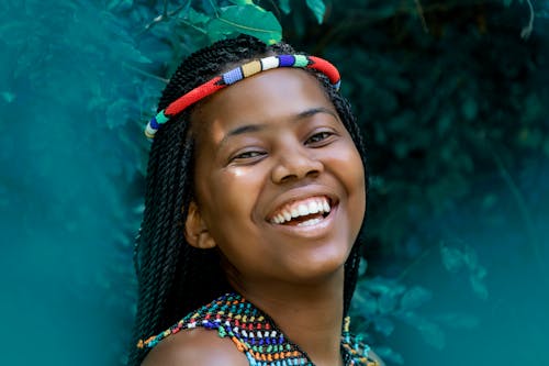 A Woman Wearing Colorful Beaded Headband and Necklace Smiling to the Camera