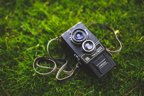 Free Retro Lubitel camera resting on lush green grass, capturing a nostalgic feel. Stock Photo