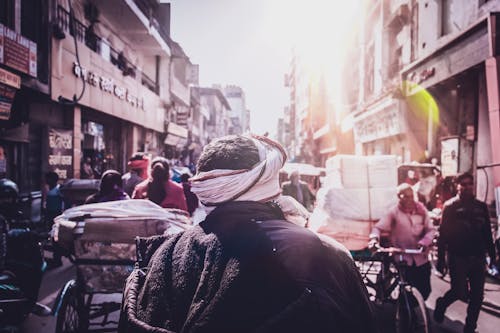 Anonymous indigenous people walking on old city street in sunlight