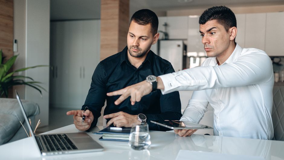 Two businessmen engage in a strategy discussion, pointing at a laptop screen. Two businessmen engage in a strategy discussion, pointing at a laptop screen.