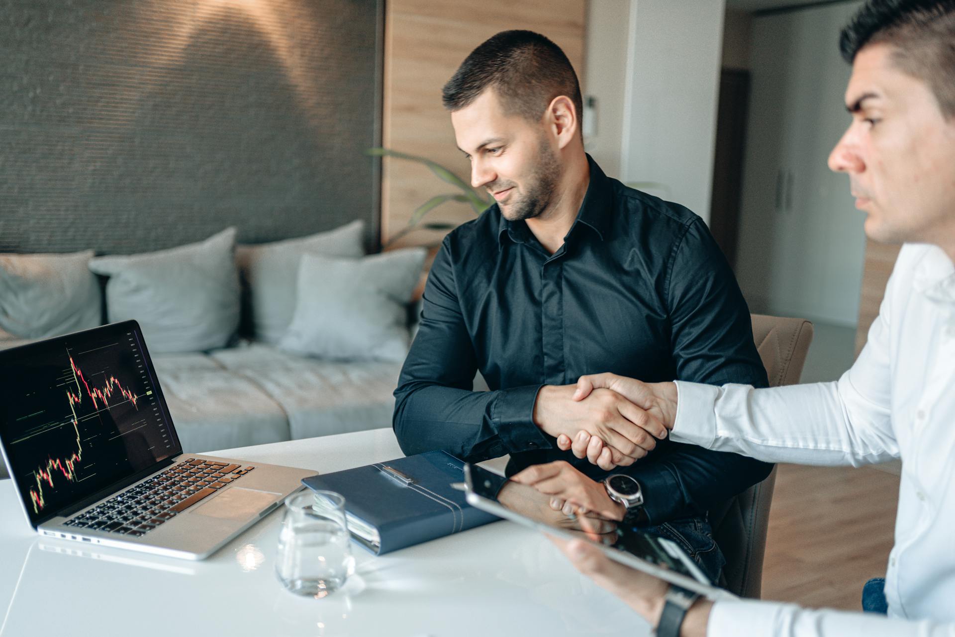 Two men in an office setting sealing an investment deal with a handshake.