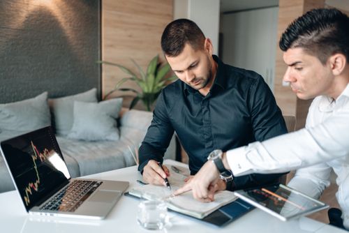 Free Two businessmen analyzing financial data on a laptop during a meeting. Stock Photo