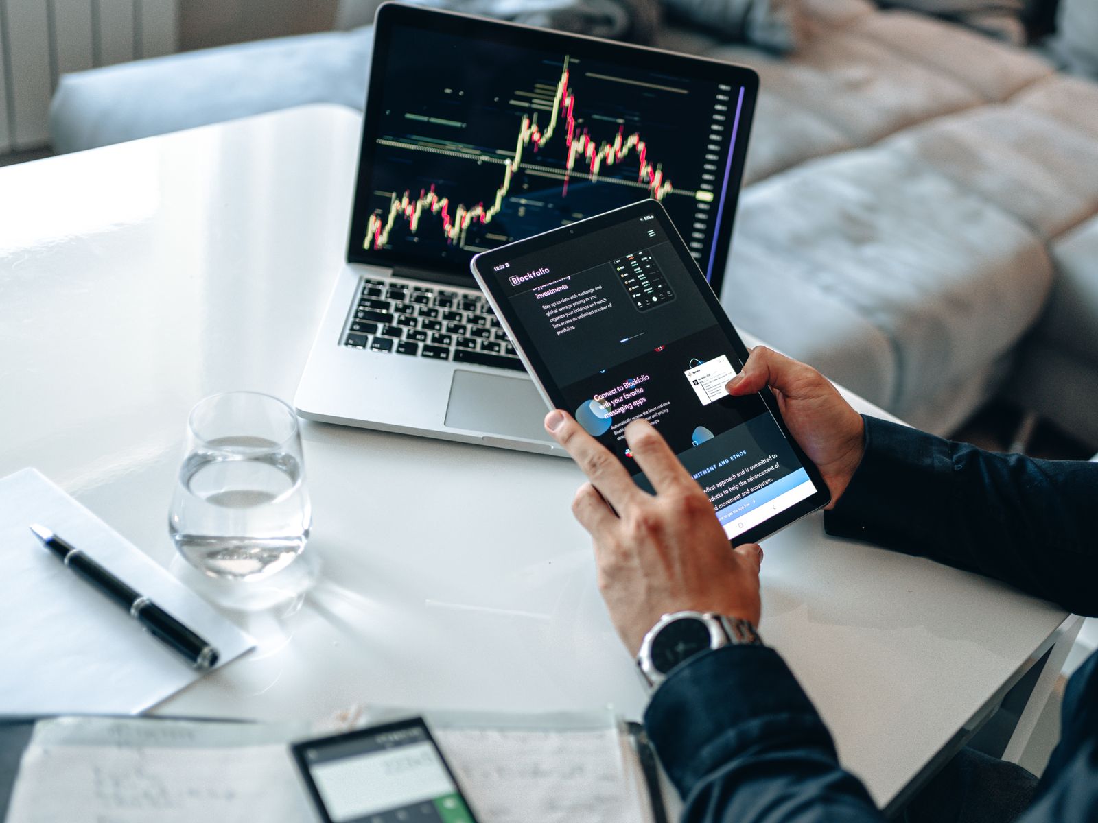 Free Person analyzing digital market trends on tablet with laptop showing financial charts. Stock Photo