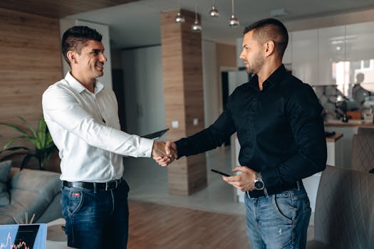 Two business professionals shaking hands in a modern office environment, symbolizing partnership.