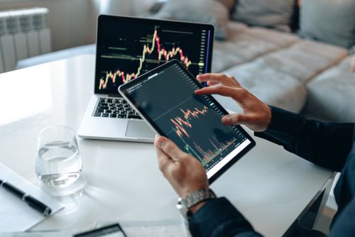 Free Trader analyzing stock market data on tablet with laptop in background. Stock Photo