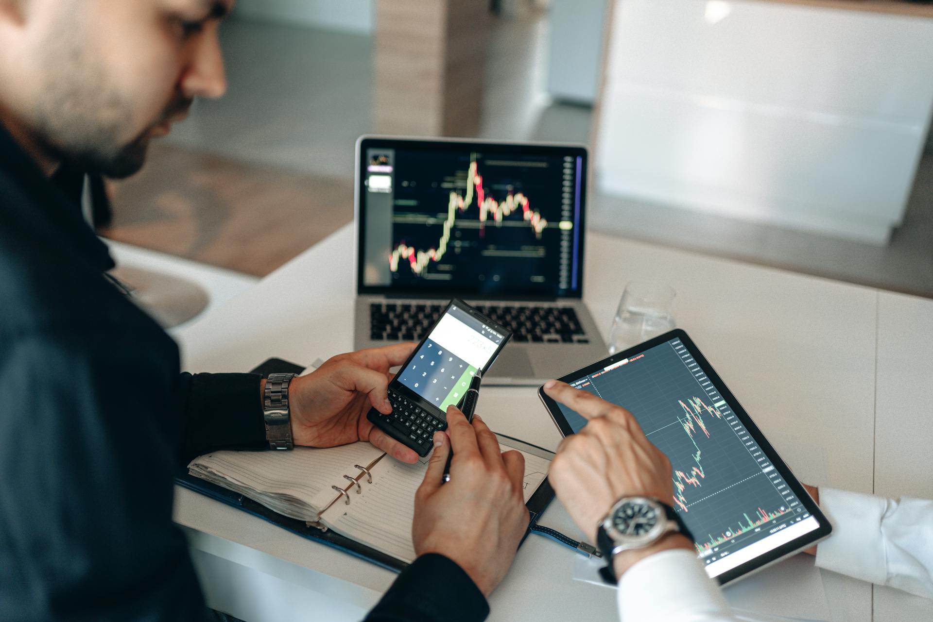 Two professionals examining financial data on digital devices at a modern office.