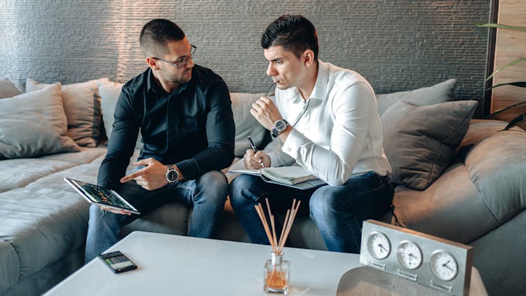 Two Businessmen Sitting On The Gray Sofa