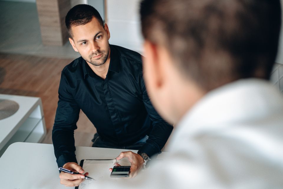 Consultant and client discussing a plan across a meeting table