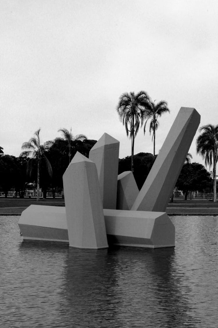 Black And White Photo Of An Abstract Sculpture In Water And Palm Trees