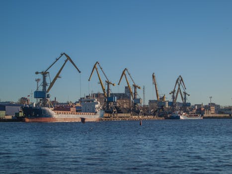 Image of an industrial shipyard with cranes and ships on a sunny day.