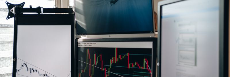A home office setup featuring multiple monitors displaying trading charts and data analysis.