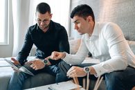 Man in Black Long Sleeve Shirt Pointing Tablet to Man in White Long Sleeve