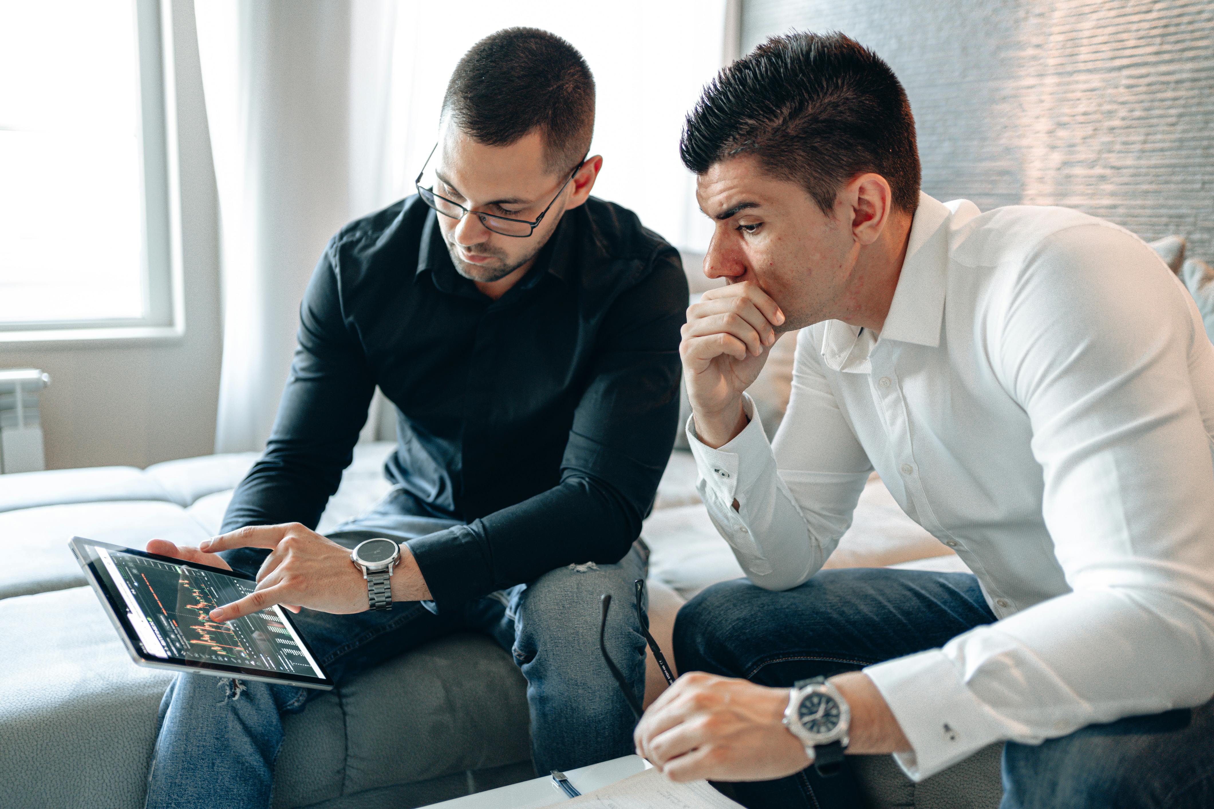 two men discussing graph on ipad