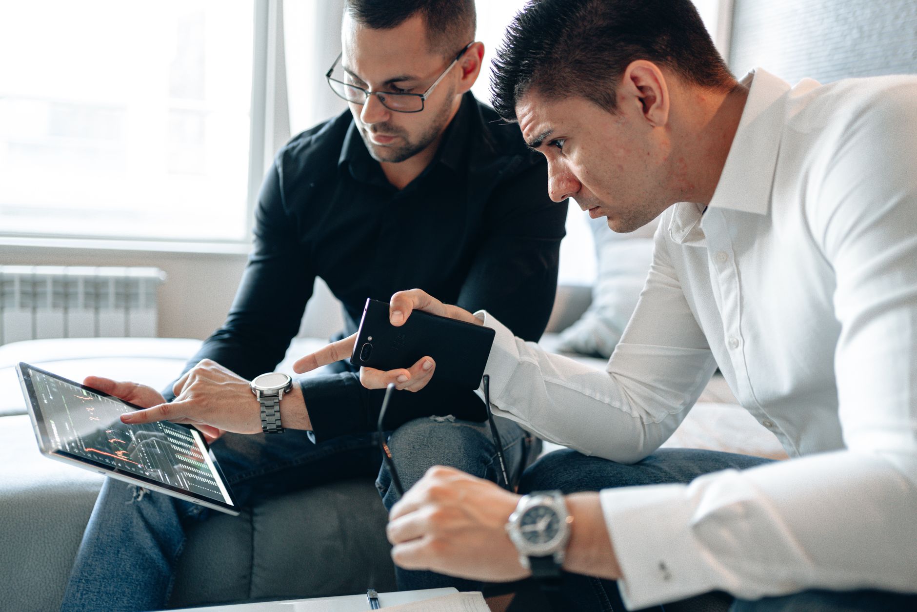 Two men analyzing financial data on a digital tablet indoors in a professional setting. (Photo by AlphaTradeZone on Pexels)