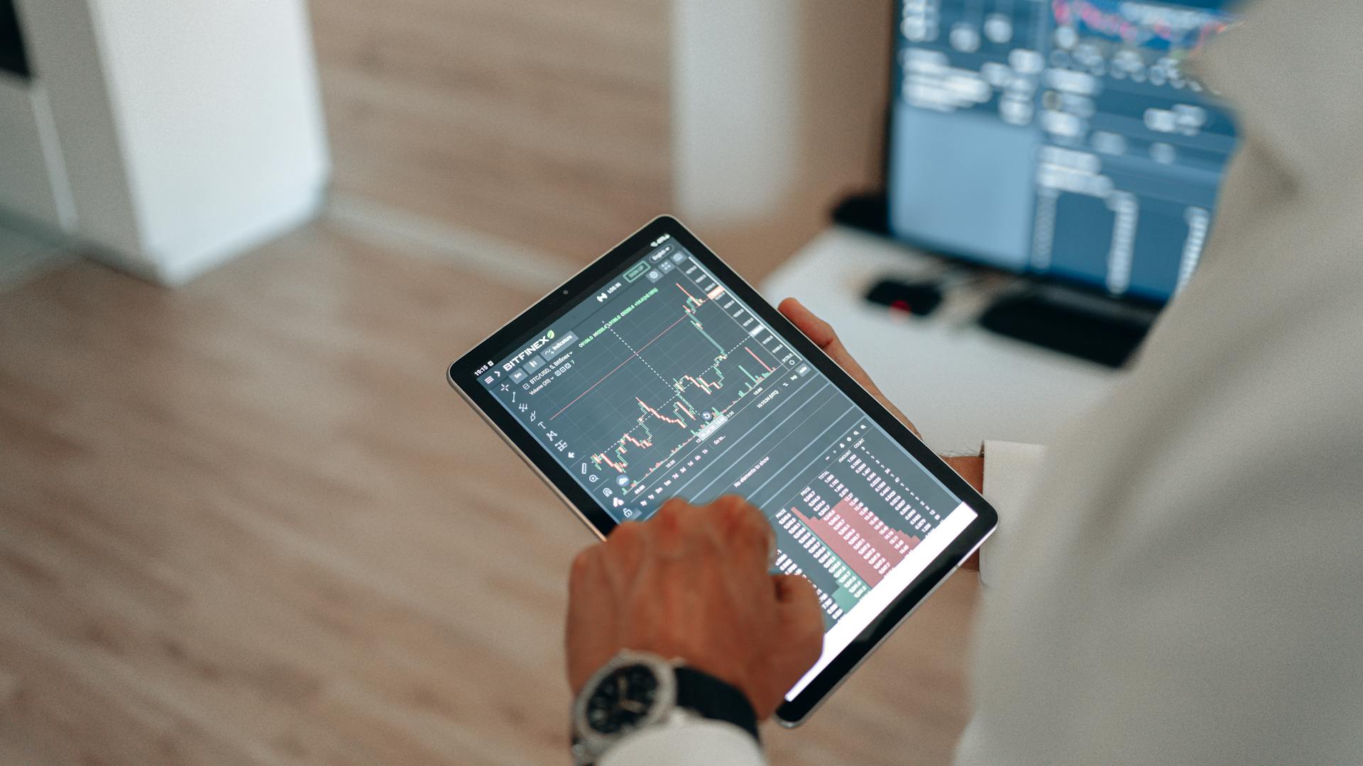 Close-up of hands using a tablet for online trading and market analysis.