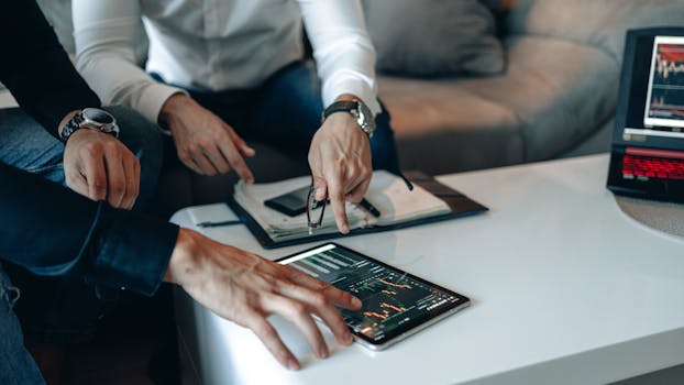 Two businessmen using a tablet to analyze financial data indoors.