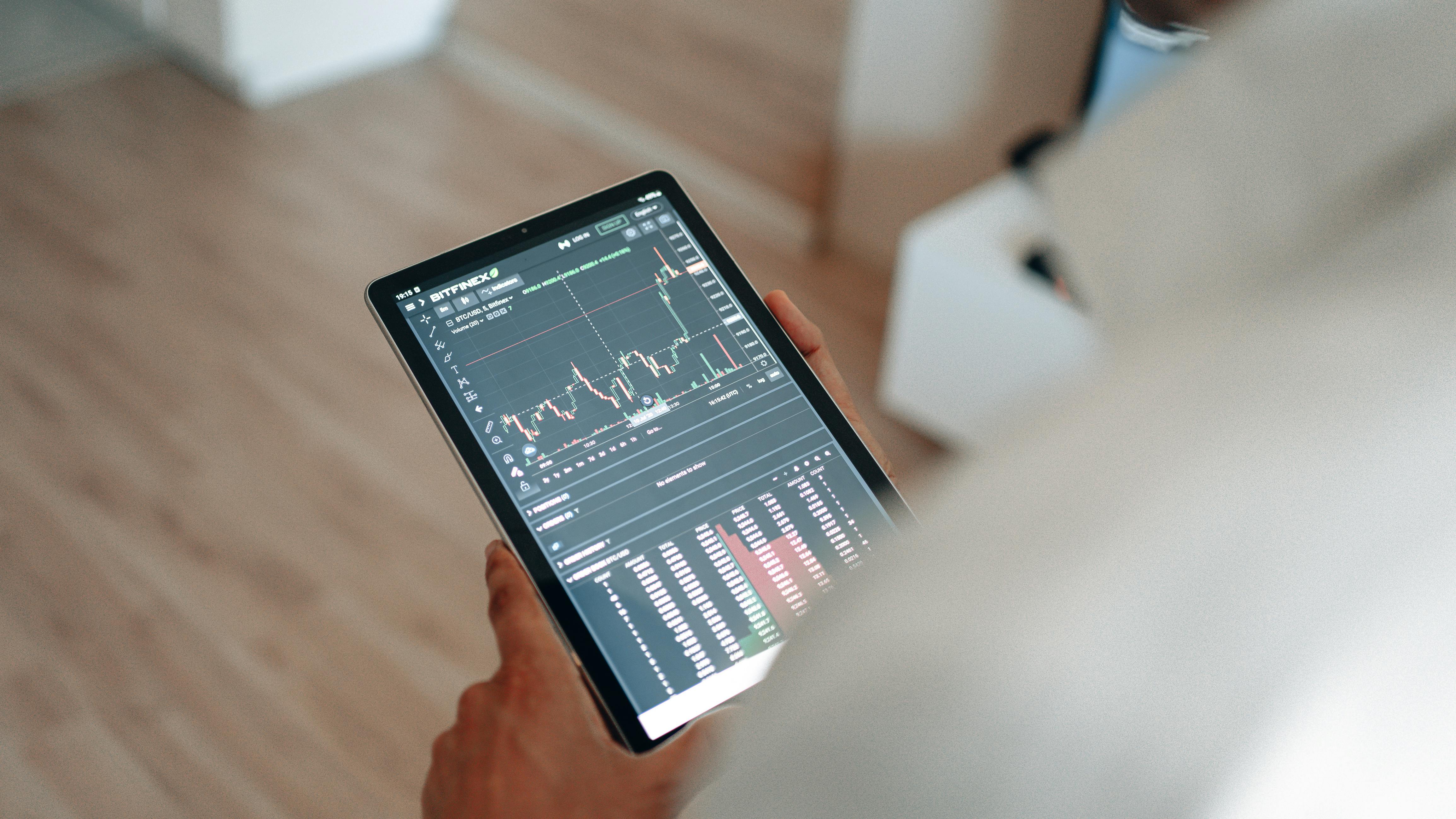 hand holding black tablet with graph on screen