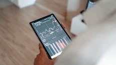 Hand Holding Black Tablet with Graph on Screen