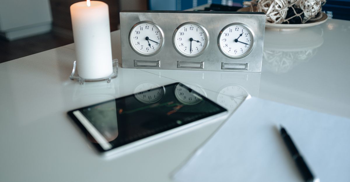 Modern office desk with candle and clocks reflecting light for a peaceful ambiance.