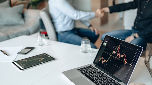 Colleagues shaking hands over technology-driven business meeting.