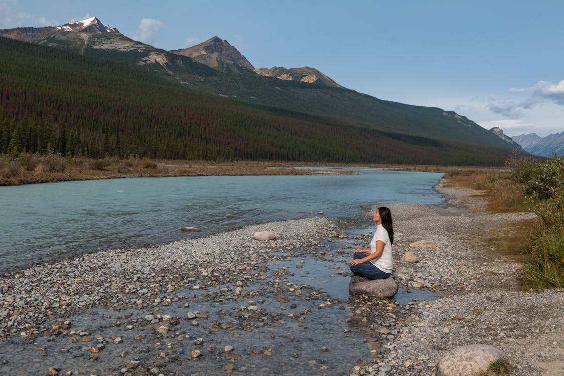 Woman Sitting on a Rock near a Body of Water