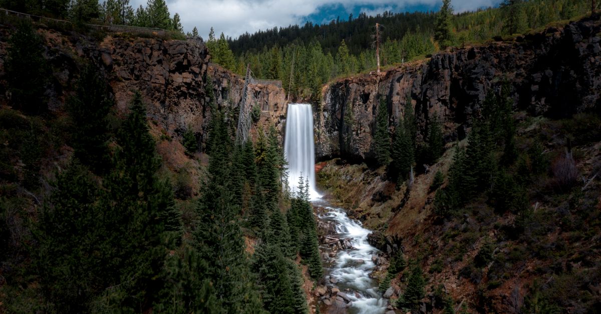 Stunning view of Tumalo Falls surrounded by rocky cliffs and lush forest in Bend, Oregon.