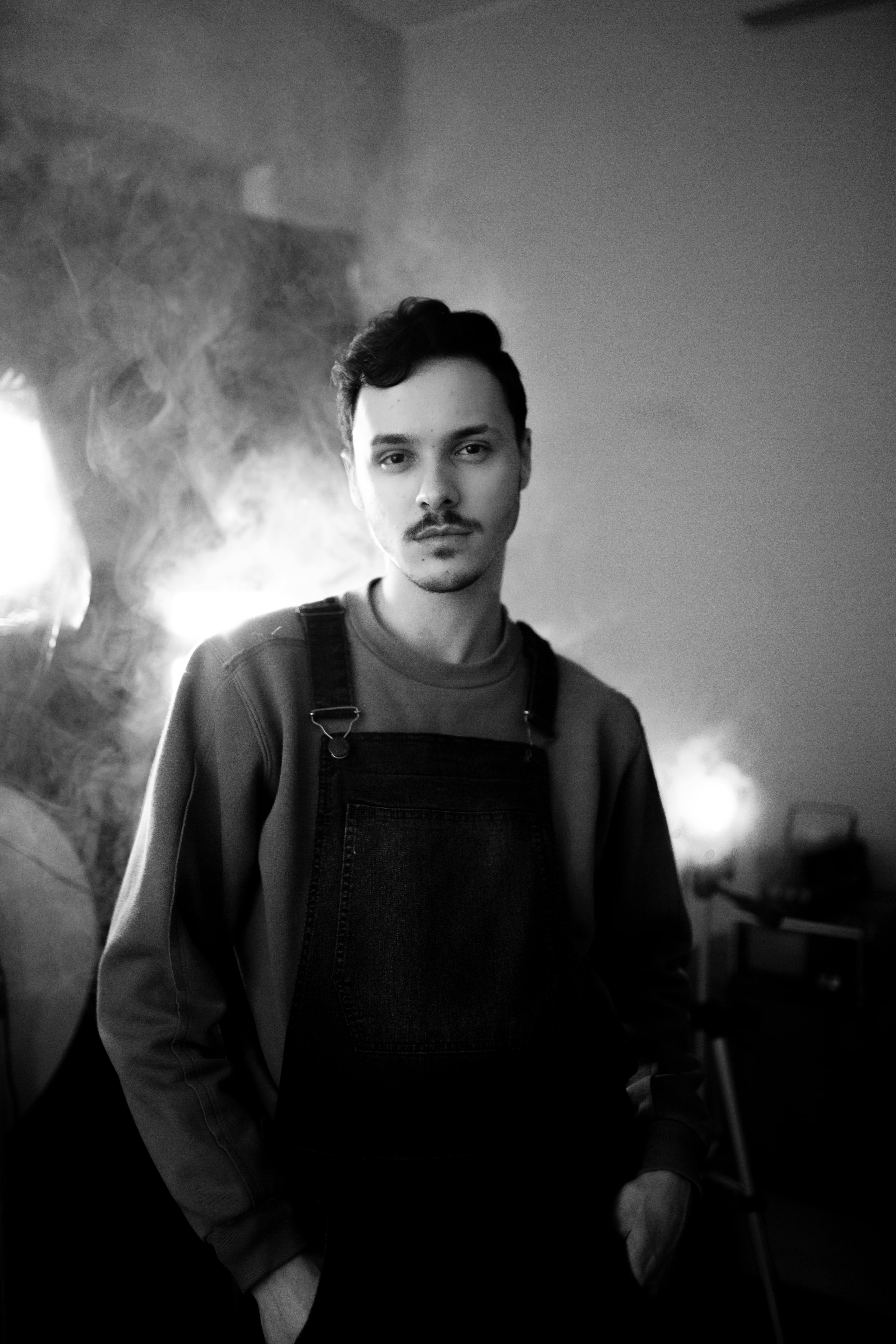 Black and white portrait of a man in overalls with a calm expression.