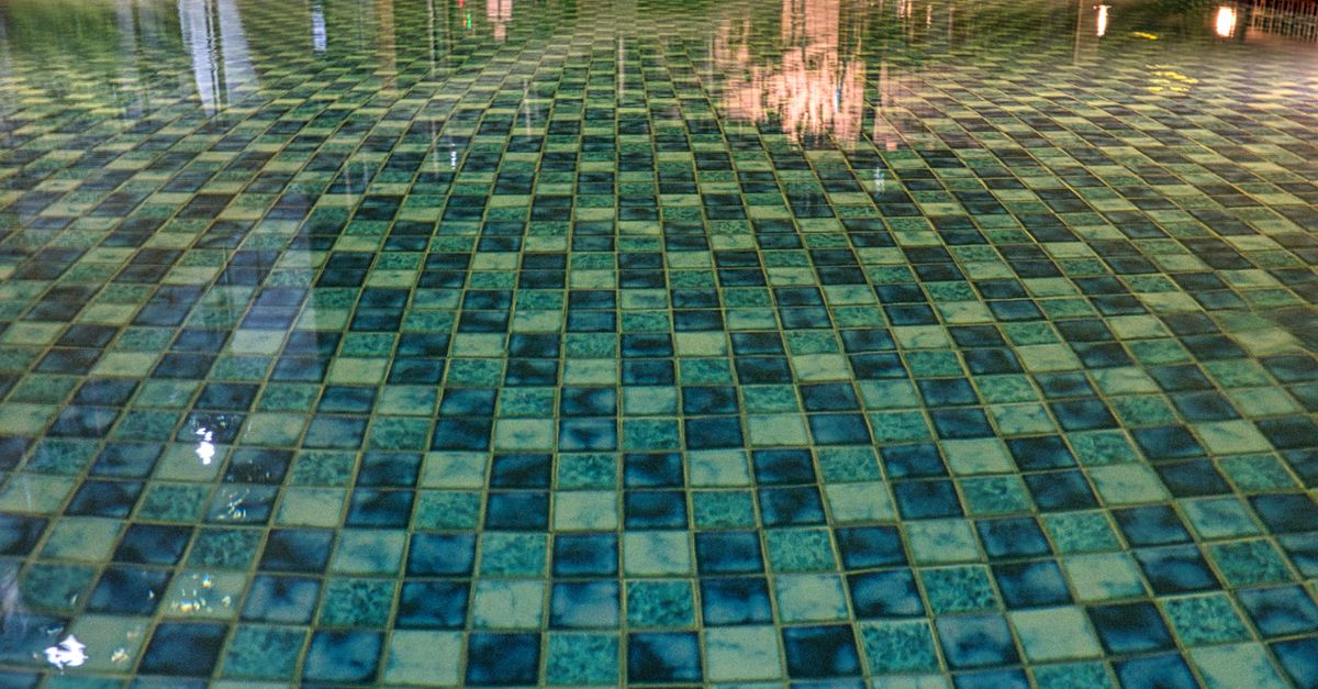 A swimming pool with a geometric pattern of tiles reflecting soft light