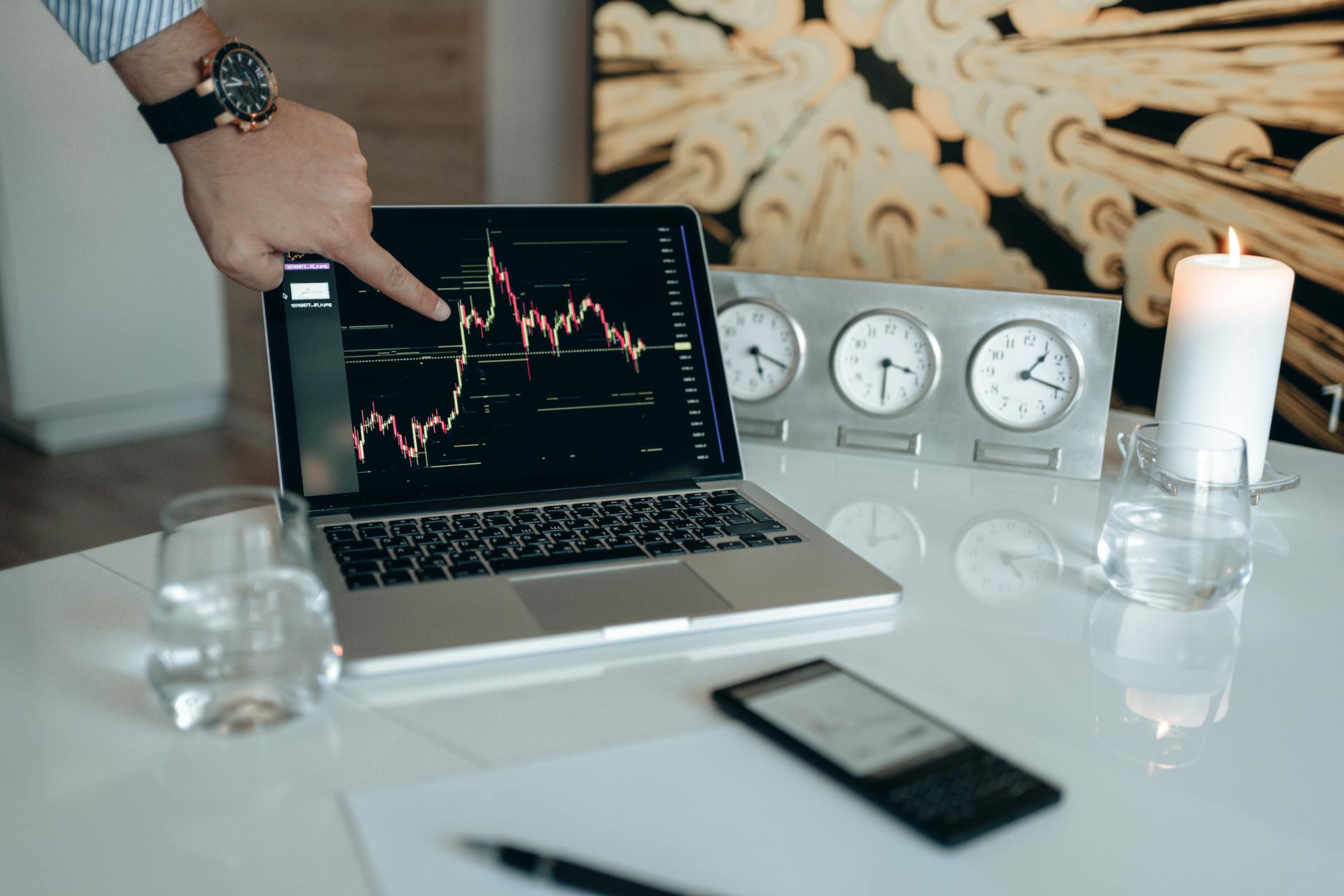 A businessman points to a stock chart on a laptop screen, indicating market analysis insights.