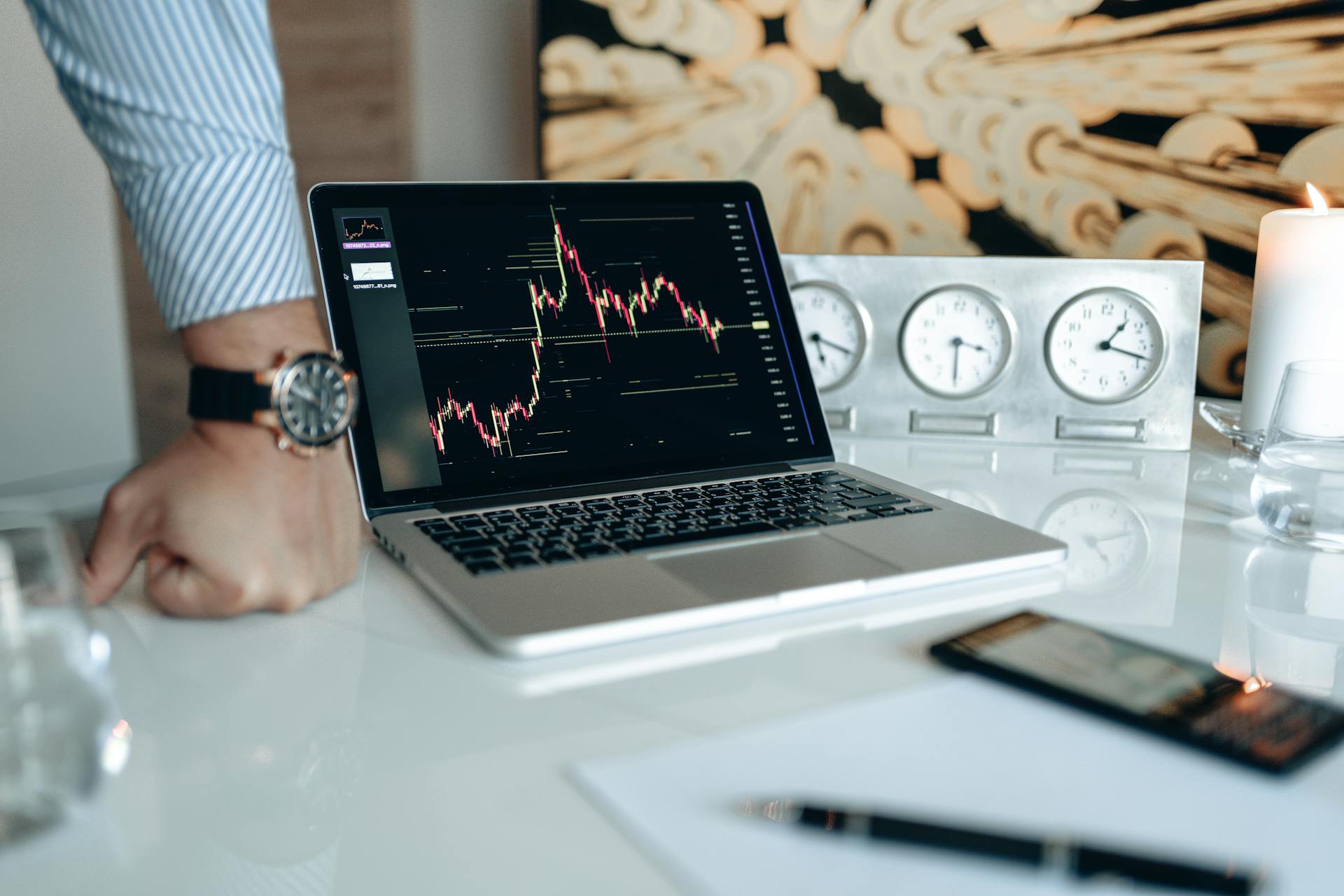 Modern office setup featuring a laptop and world clock, ideal for finance or trading.