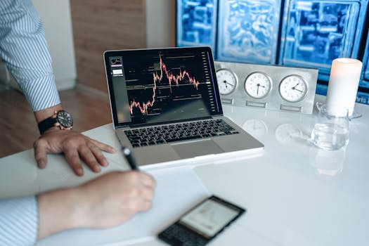 Person analyzing stock market graph on laptop in modern office setting with clocks and candle.