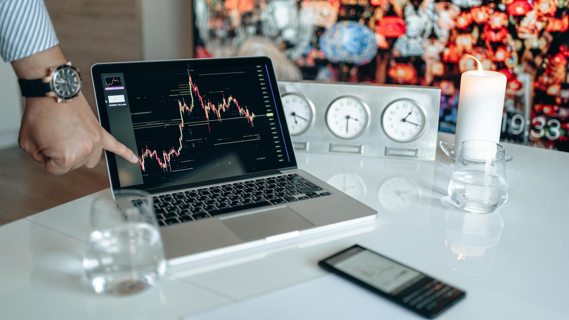 Businessman pointing at a financial graph on a laptop screen, showcasing stock market analysis.