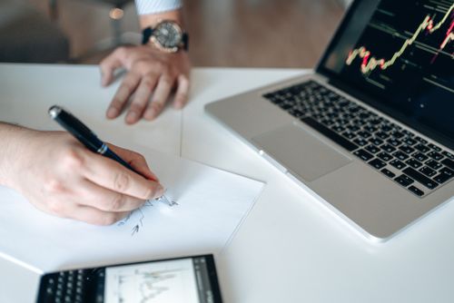 Free Hands analyzing financial data at a desk with a laptop and calculator. Stock Photo