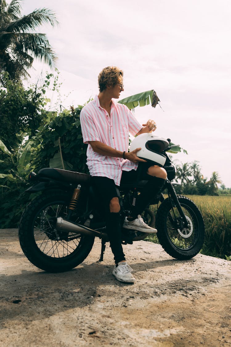 Man In Pink And White Polo Posing On His Motorcycle