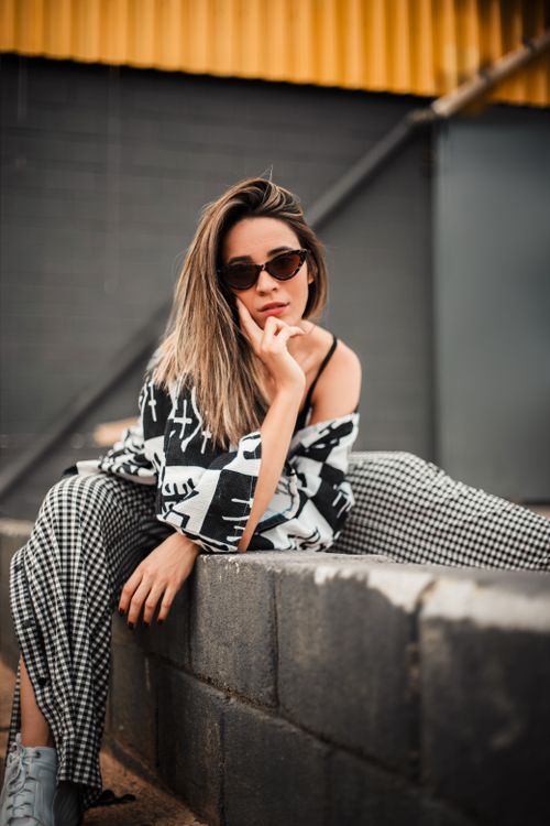 Free Trendy woman in sunglasses poses against a brick wall, exuding modern fashion vibes. Stock Photo