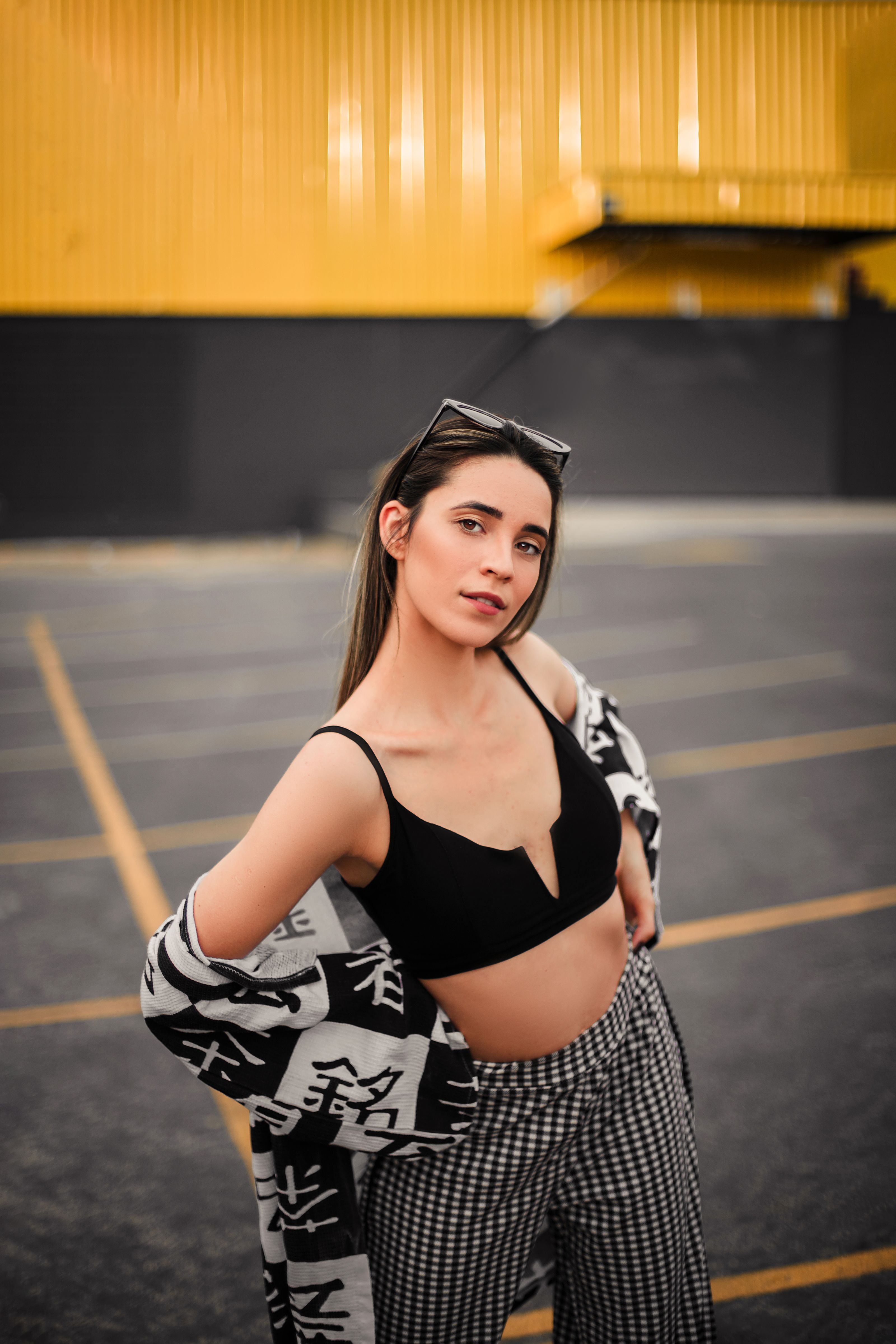 Jovem mulher estilosa posando com confiança ao ar livre com um fundo urbano moderno.