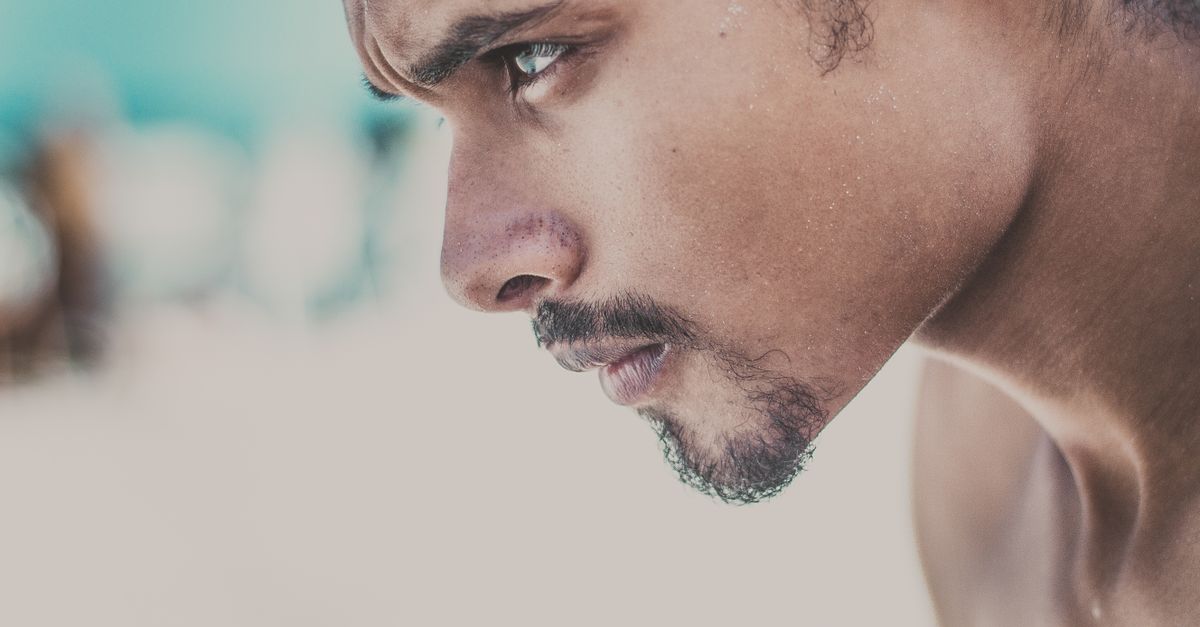 A close-up side view of a young man with a serious and focused expression