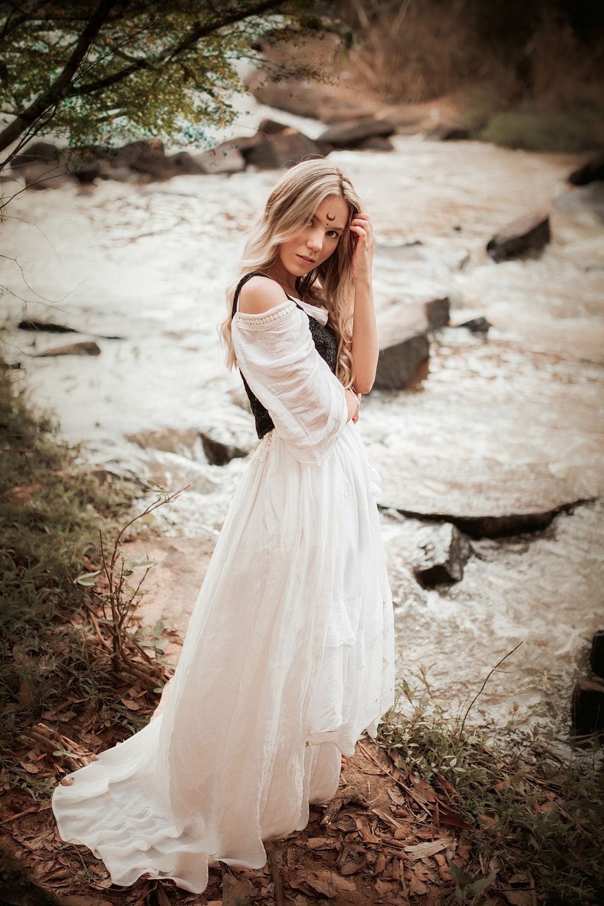 A woman in a white boho dress standing in nature — ethereal and dreamy