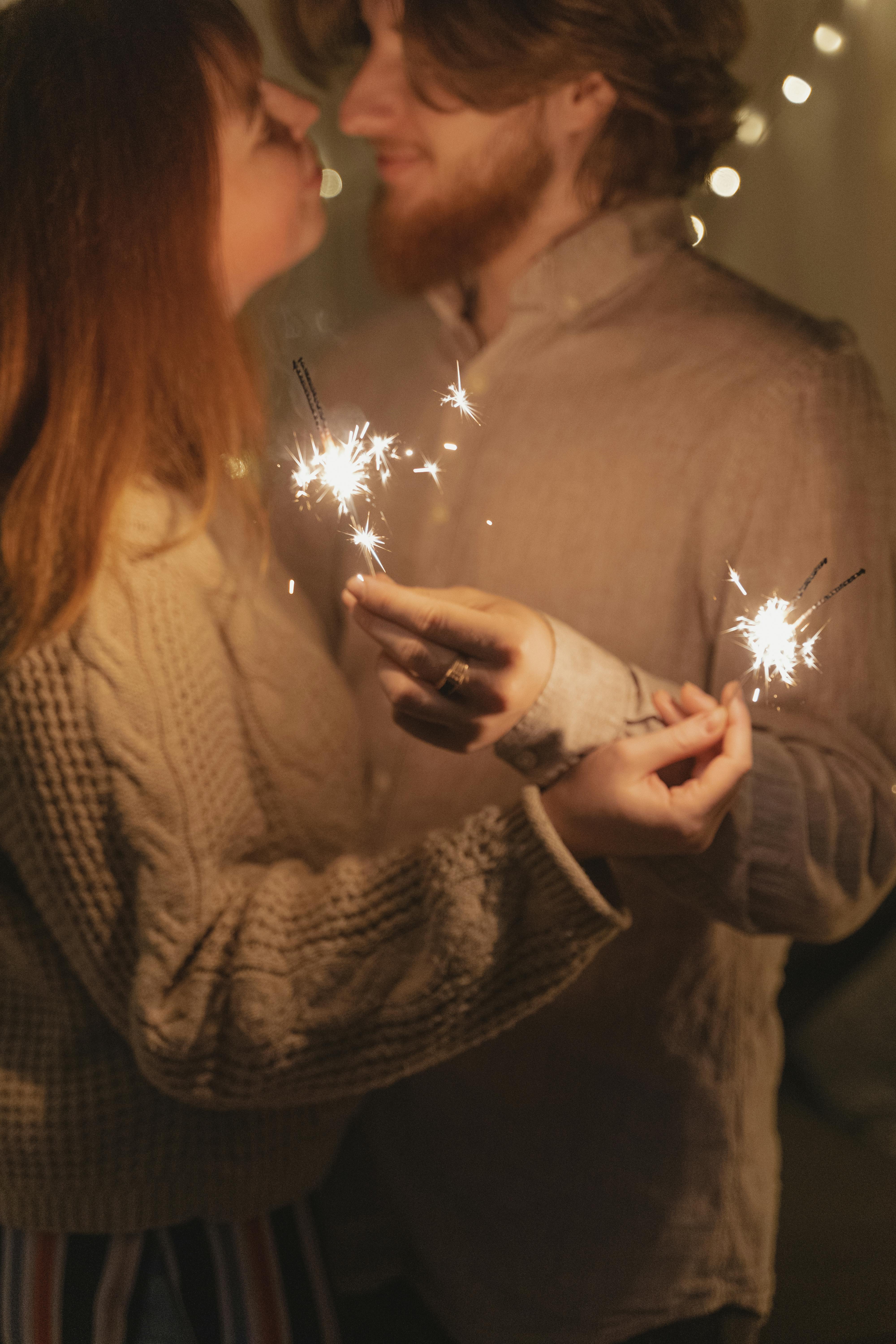 couple kissing while holding lighted sparkler