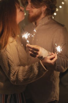 A loving couple shares a moment with sparklers indoors, creating a festive and romantic atmosphere.