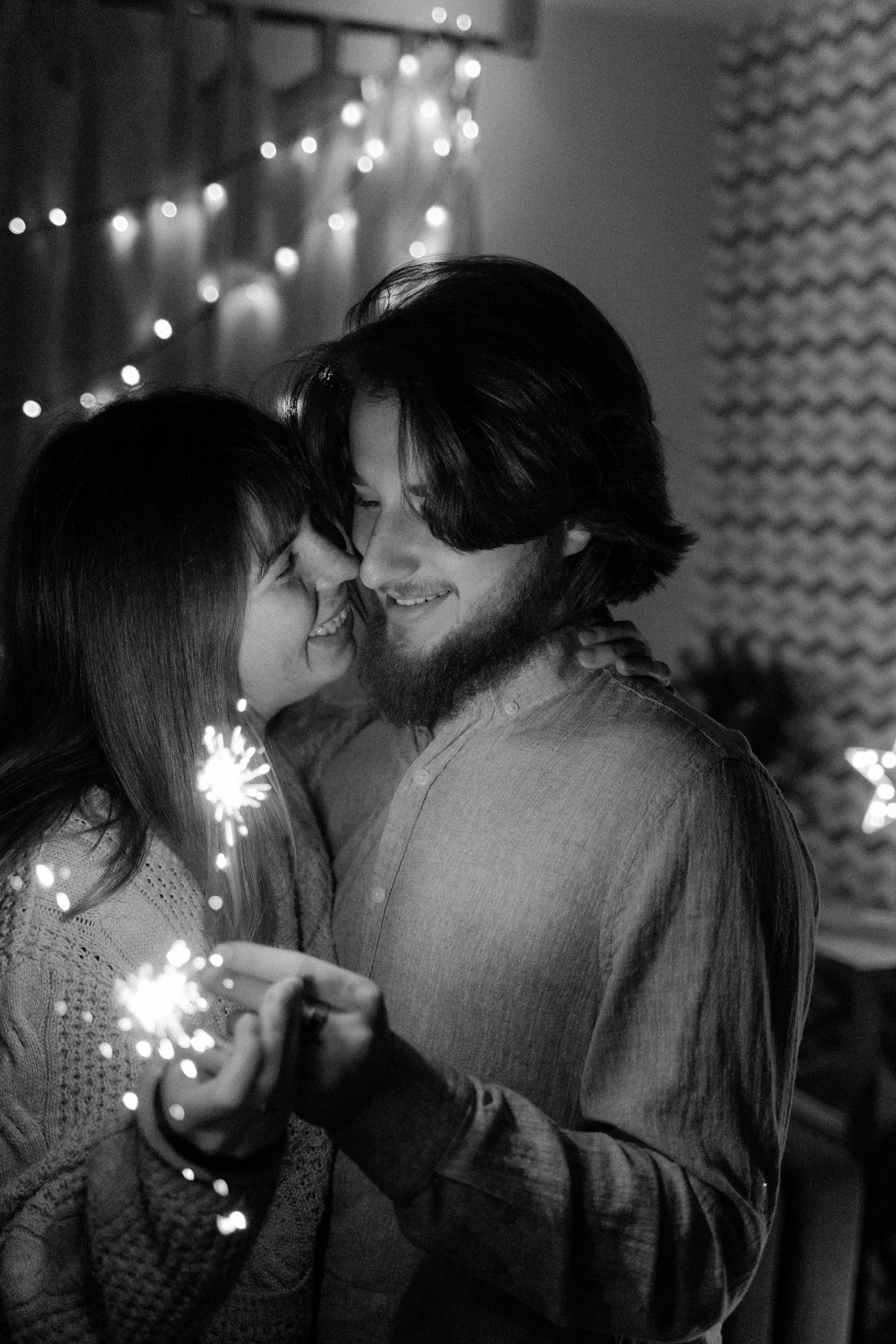 grayscale photo of a couple looking at each other while holding sparkling sticks